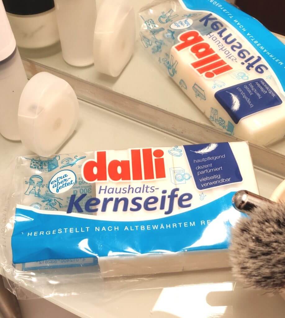 A package of Dalli bar soap beside some dental floss and a shaving brush