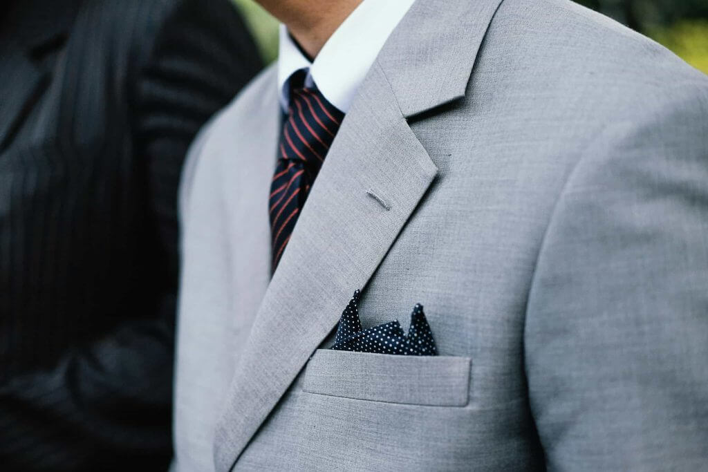 A man wearing a gray suit jacket with notched lapels.