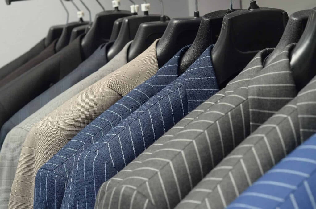 Suit jackets of various patterns, colors and fabrics on hangers.