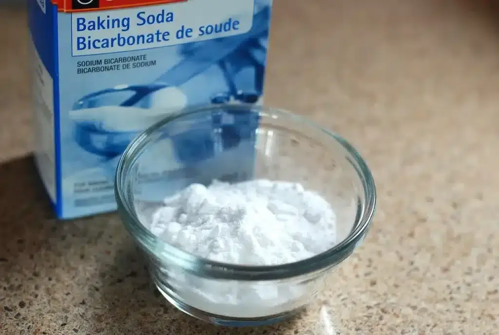 A box of baking soda, and a small glass bowl containing baking soda