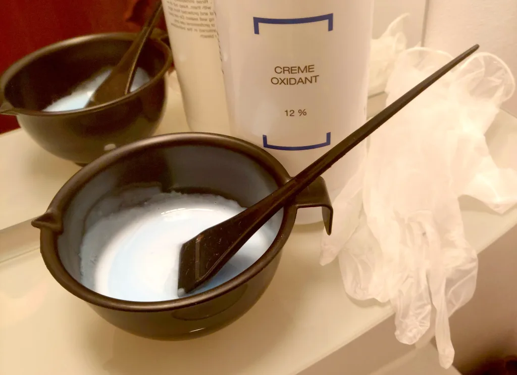 Tinting brush and bowl containing bleaching solution, and a bottle of 40 volume (12%) developer