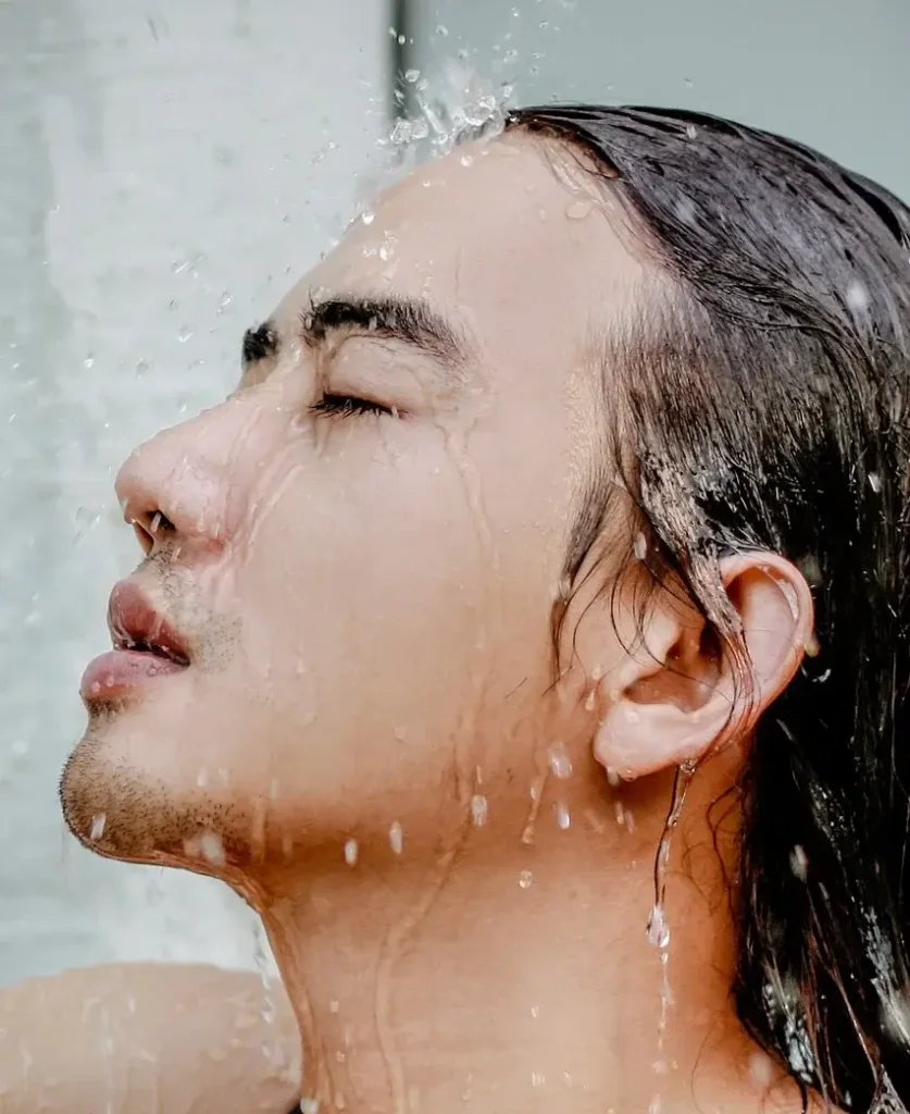 Man showering with cold water, which keeps blood vessels elastic as well as constricting them in order that they're less visible.