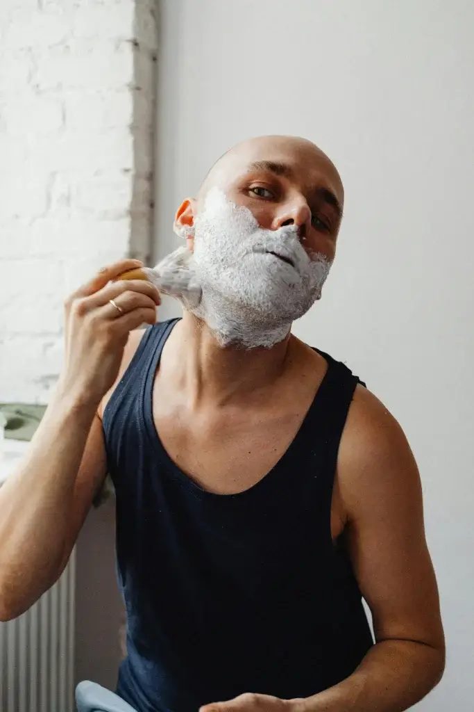 A man lathering up with a brush and shaving soap.