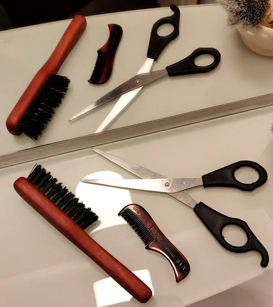 From left to right: a boar bristle beard and mustache brush; a hand sawn mustache comb; and a pair of beard and mustache scissors. All essential tools for a thicker mustache.