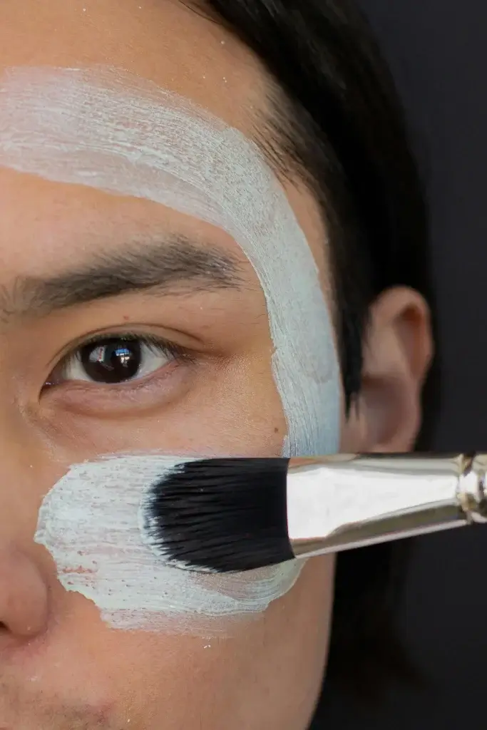 Man applying a clay mask with an application brush.