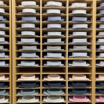 A wooden shelving unit displaying neatly folded dress shirts in various colors and patterns, highlighting the diversity of dress shirt colors for professional wear.