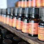 Assorted bottles of pure essential oils on a wooden shelf, ideal for men’s well-being and grooming.