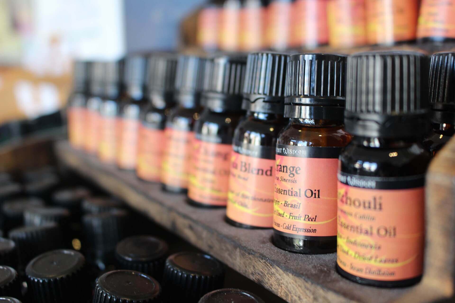 Assorted bottles of pure essential oils on a wooden shelf, ideal for men’s well-being and grooming.