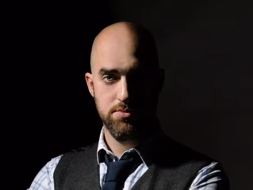 Confident bald man in a dress shirt and tie, showcasing the results of a clean head shave—what is the best way to shave your head?