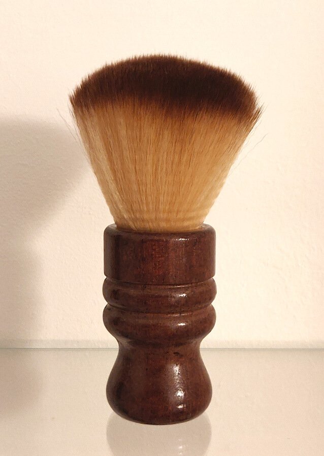 A Barber's neck duster with a wooden base.