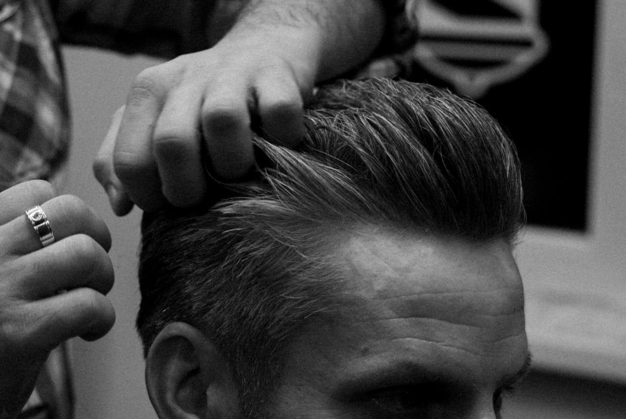 Well-maintained hair being styled at a barbershop, reflecting the impact of consistent healthy hair tips for men.
