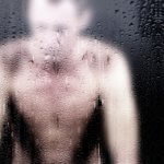 Man behind fogged glass in a shower setting, symbolizing the emotional impact of "old people smell" and the struggle to get rid of it.