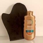 Garnier Ambre Solaire Natural Bronzer self-tanning lotion with a black mitt—used to apply self-tanner evenly for streak-free, professional-looking results.