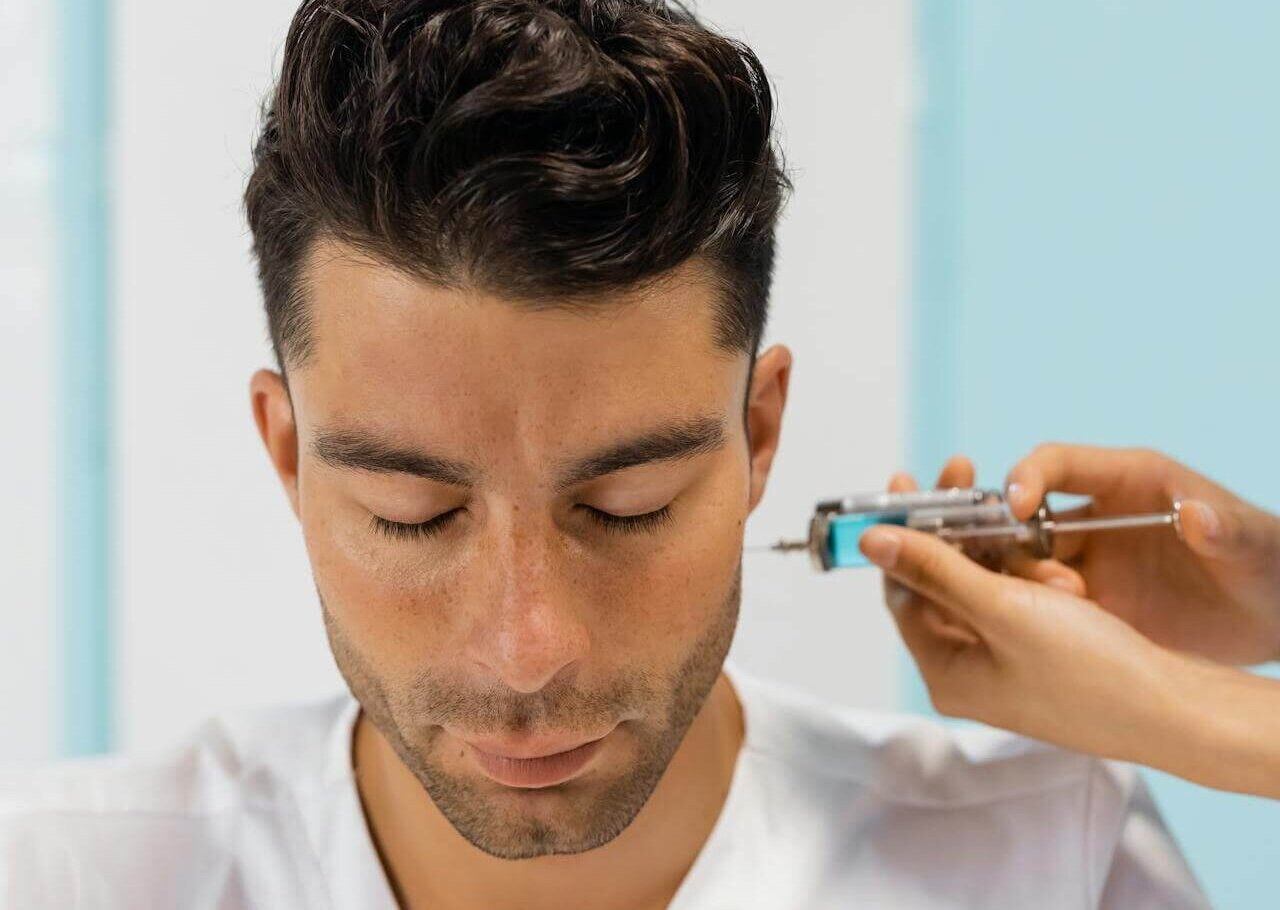 Man receiving a noninvasive facial treatment near the temple—typical of lunchtime cosmetic procedures.