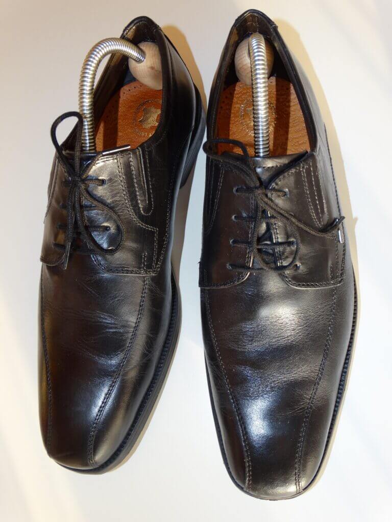 A pair of men's well-worn and broken in dress shoes with shoe trees to preserve shape.