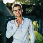 Well‑groomed man in sunglasses and a light blue shirt outdoors, representing how to look good every day.