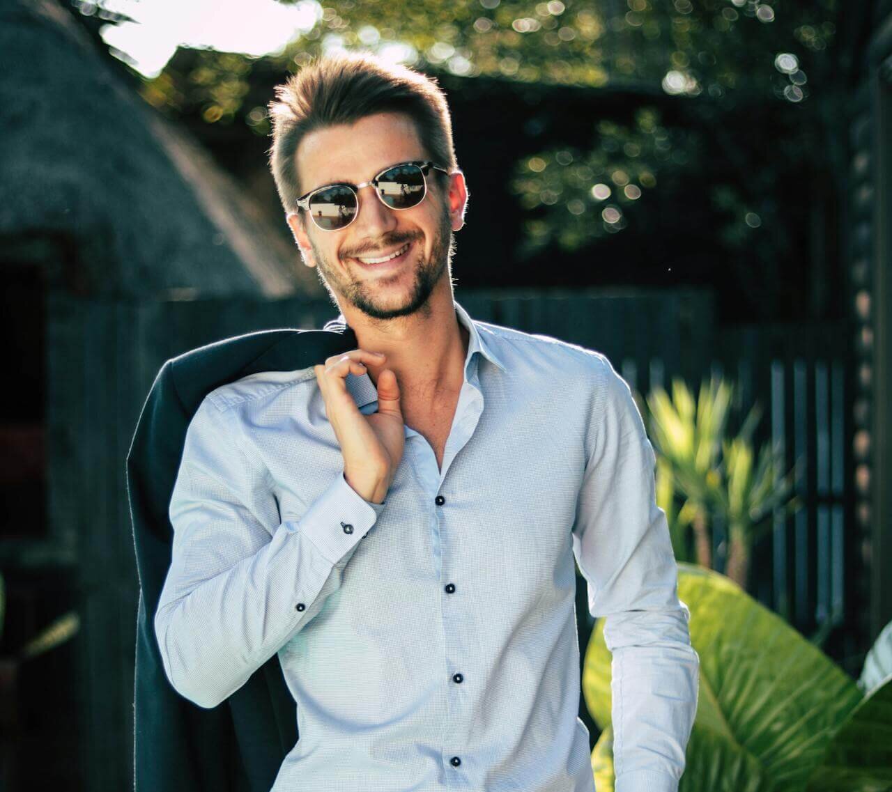 Well‑groomed man in sunglasses and a light blue shirt outdoors, representing how to look good every day.