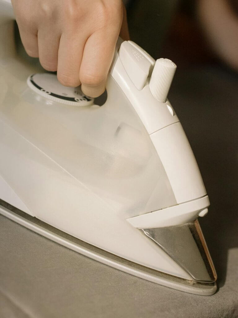 Hand pressing steam iron against fabric—an everyday household chore to increase NEAT.