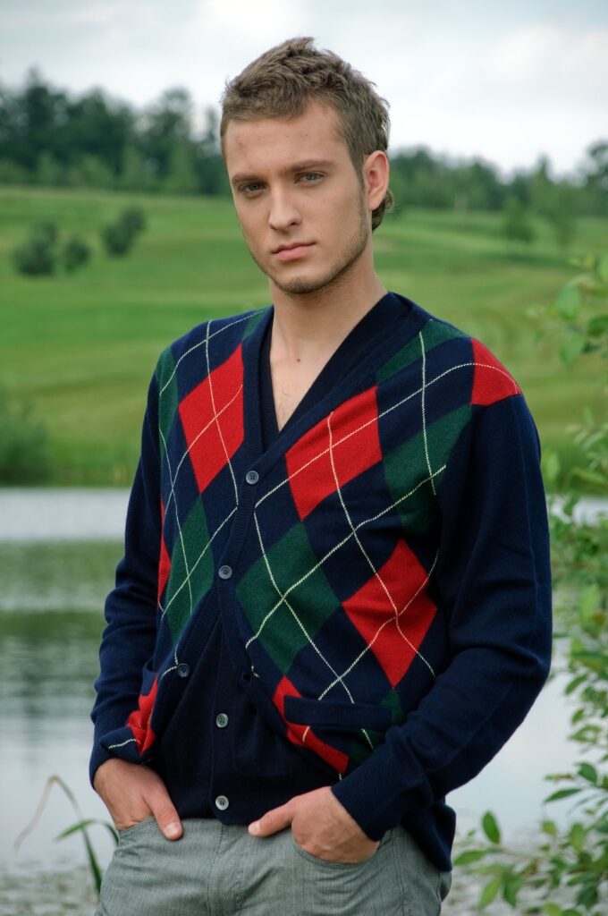 A man wearing a V-neck cardigan featuring an argyle pattern.