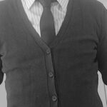 The torso of a man wearing a V-neck cardigan with a striped shirt and a tie.