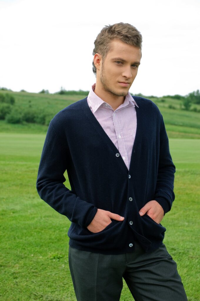 Man wearing a V-neck cardigan over a striped shirt.