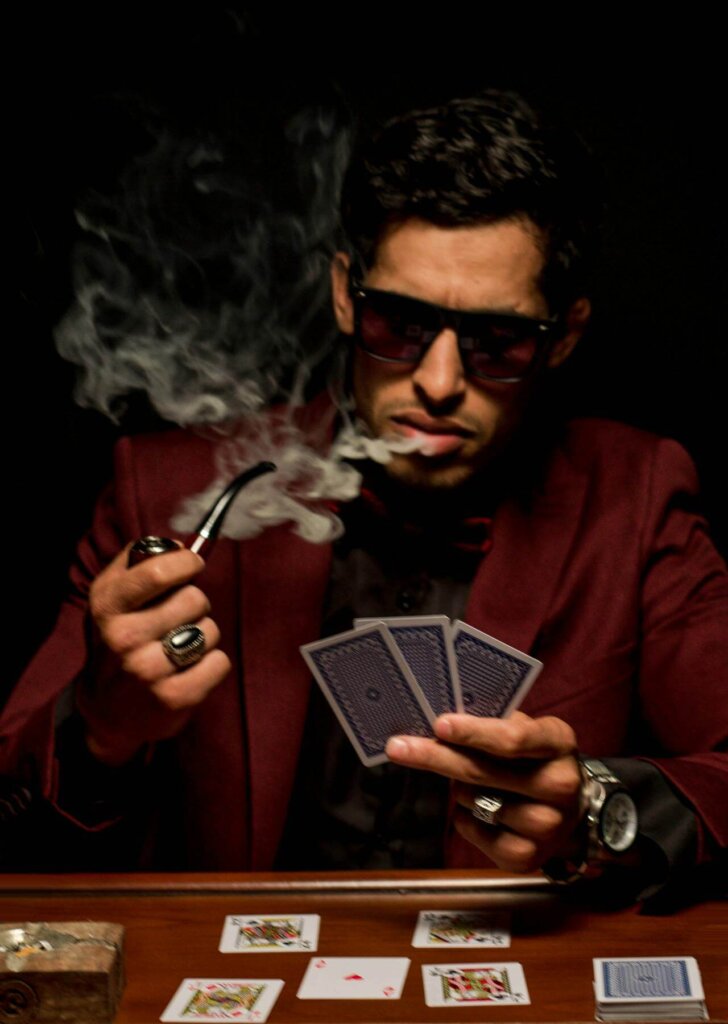 A man wearing sunglasses at a card table, using them to help maintain a poker face.