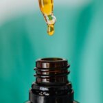 A dropper dispensing oil into a bottle, showing how to use shaving oil before shaving.