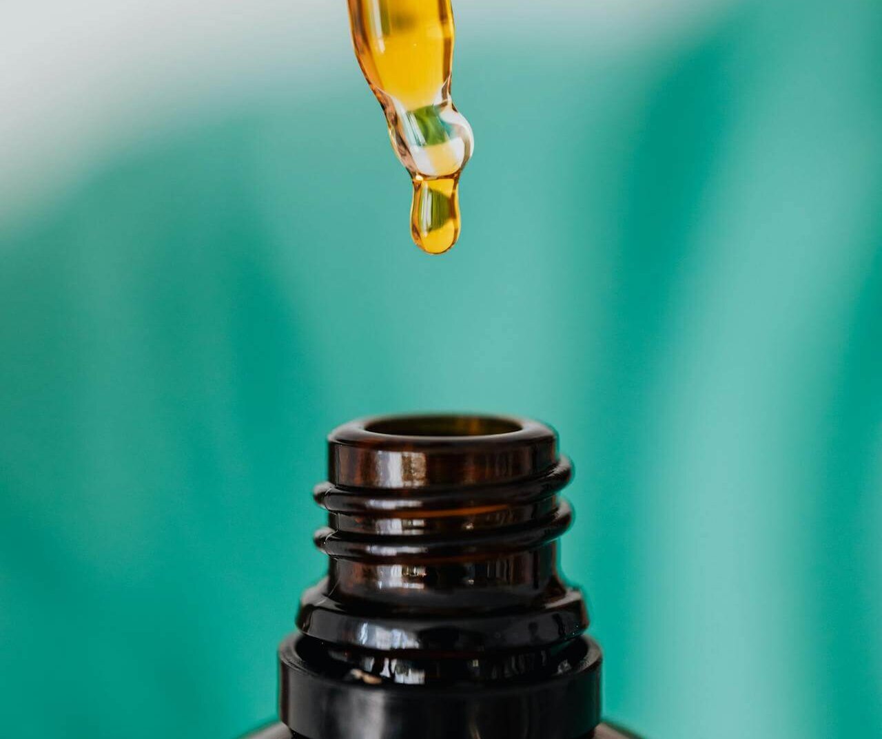 A dropper dispensing oil into a bottle, showing how to use shaving oil before shaving.