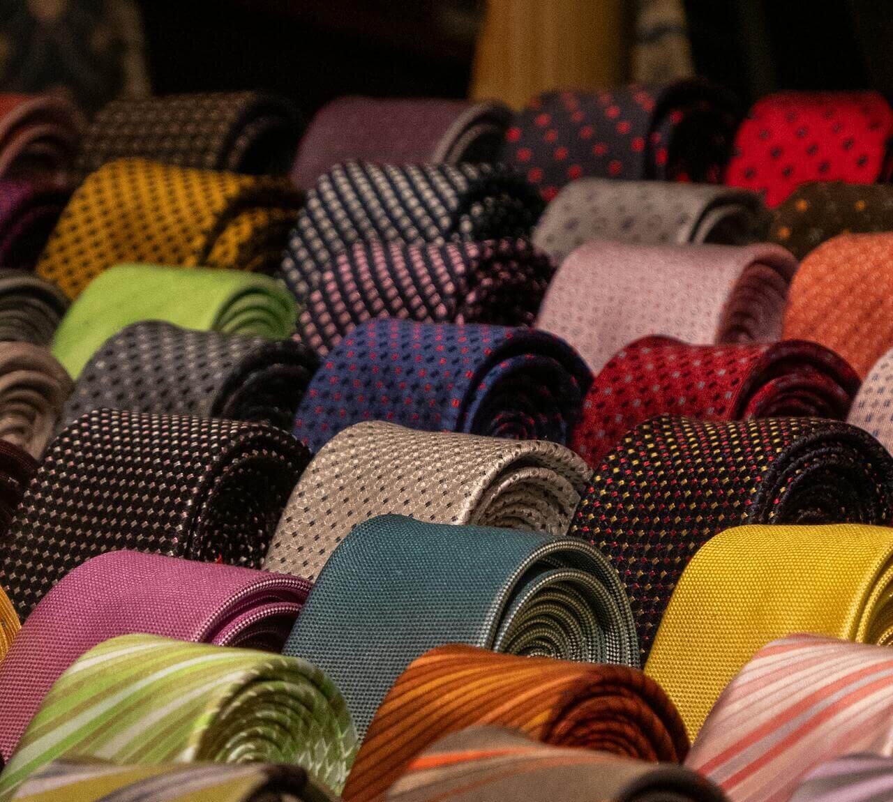 A drawer of rolled ties in various colors and patterns, demonstrating how to store and care for ties.