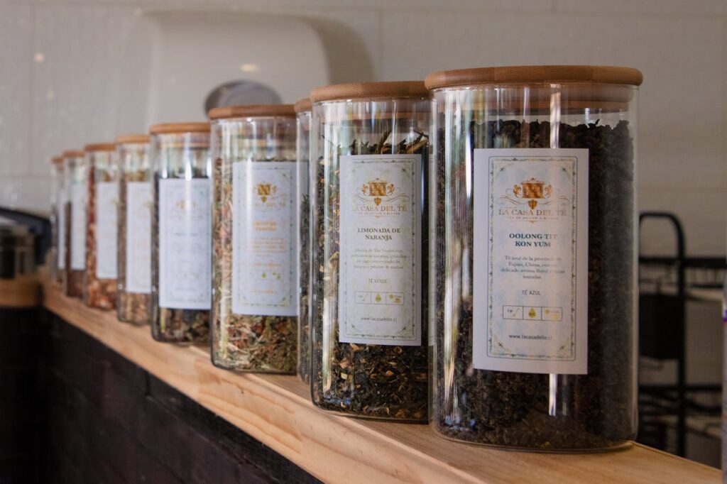A selection of teas in jars on a wooden shelf.