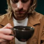 A man who is trying to reduce caffeine consumption looking thoughtfully at a cup of coffee.
