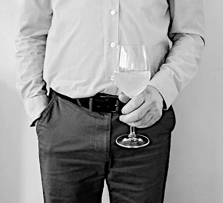 Man with one hand in his pant pocket and the other holding a drink.