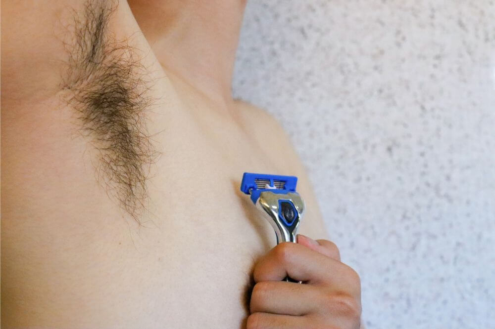 A man about to shave his armpit.