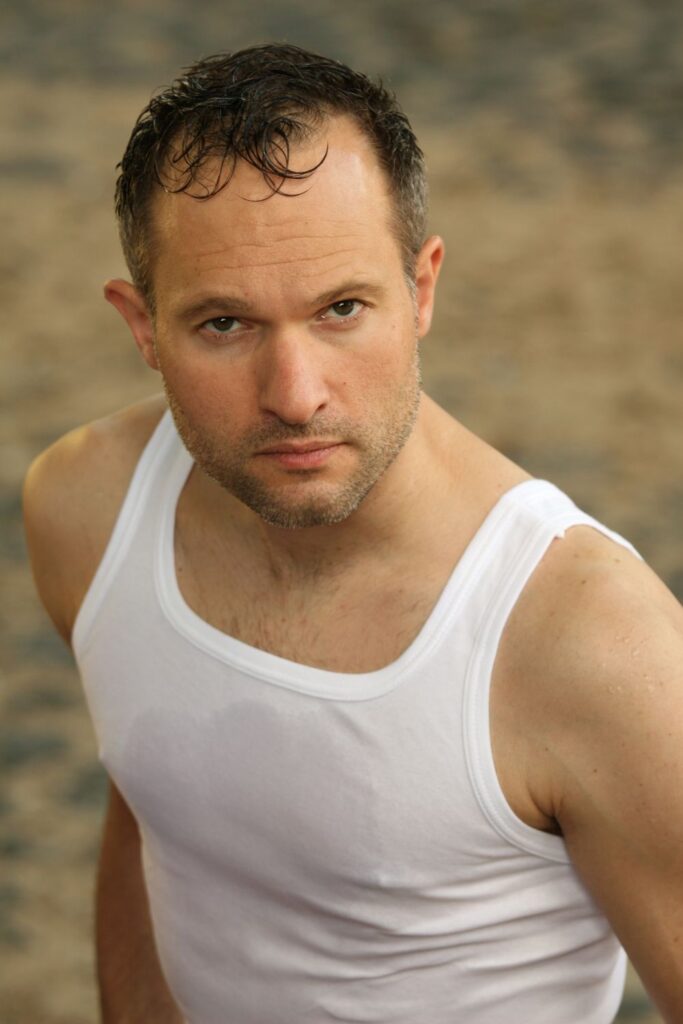 A man wearing a cotton undershirt in hot, humid weather that looks heavy and wet.