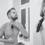 A man tidying his neckline in front of a mirror.