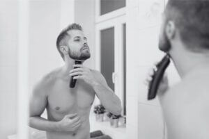 A man tidying his neckline in front of a mirror.