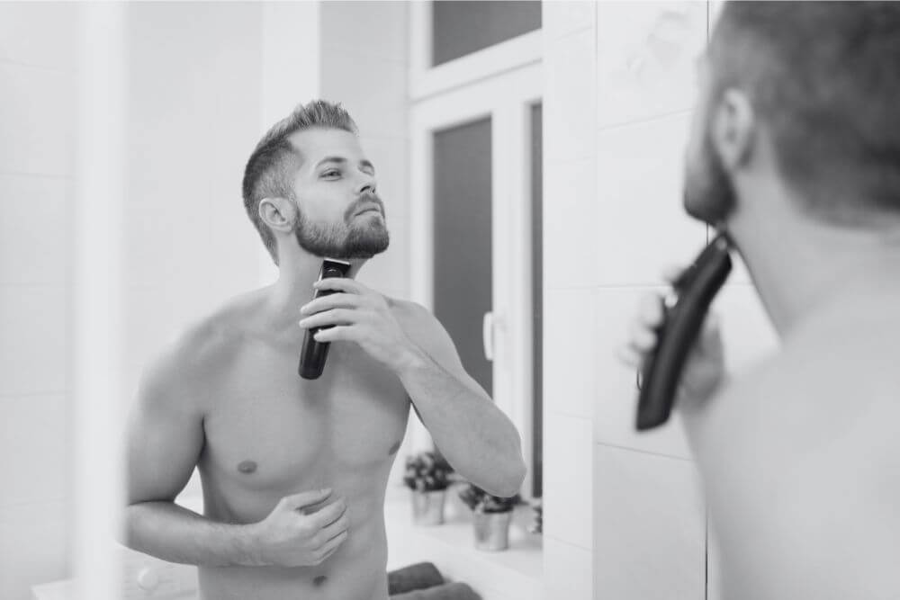 A man tidying his neckline in front of a mirror.