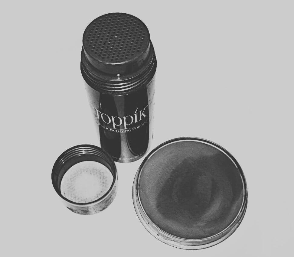 A shaker container of hair-building fibers and a compact of water-activated scalp concealer, both well-used.