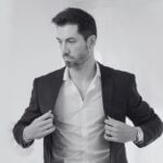 A man slipping a suit coat over a dress shirt that has a perfectly symmetrical collar and placket.