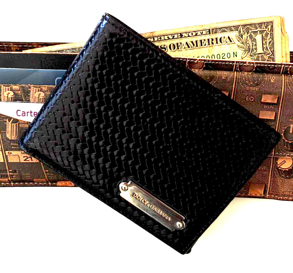 A black patent‑leather men's wallet placed on a printed wallet containing a few dollar bills and cards.